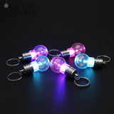 Lot de porte clé ampoule lumineux allumés en rose, violet et bleu sur fond noir
