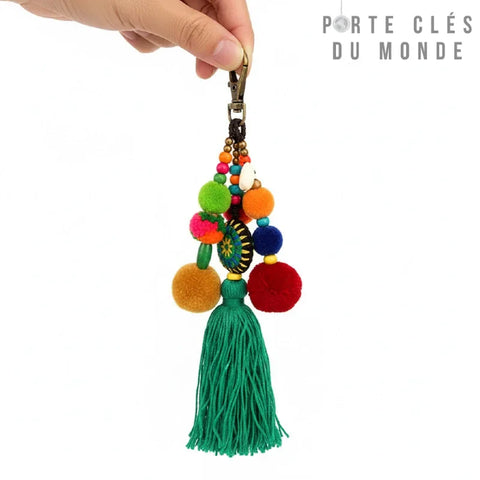 porte clé bohème tenu en main avec un pompon vert et plusieurs petits pompons multicolores 