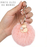porte clé pompon fourrure tenu en main sur fond blanc
