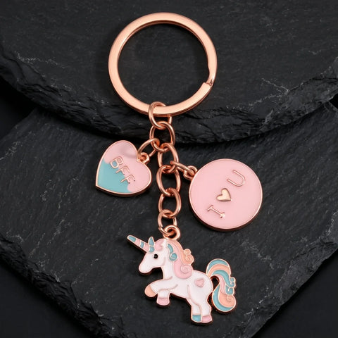 Licorne porte-clé aux détails roses et turquoise, avec cœur BFF et finition dorée rose sur fond sombre