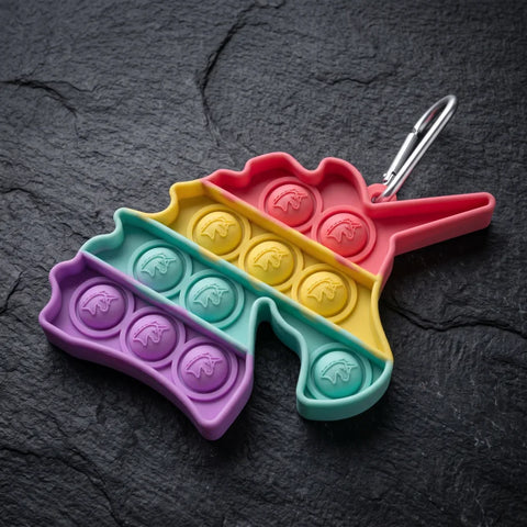 pop-it porte-clés licorne couleur arc en ciel avec mousqueton argenté sur fond sombre
