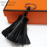 Porte clé cuir pompon noir vu de près sur fond blanc, détail du cuir et des franges élégantes