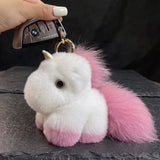 Porte clé licorne en peluche blanche et rose pastel avec queue duveteuse, accroché à une clé de voiture