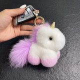 Porte clé licorne en peluche blanche et violette avec corne dorée et queue duveteuse, accroché à une clé de voiture