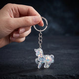 Porte clé licorne résine à paillettes multicolores tenu en main par son anneau métallique