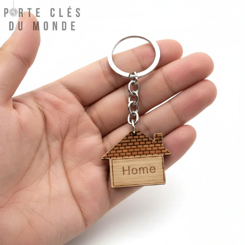 Porte-clés maison en bois tenu en main pour montrer la taille réelle et le rendu naturel sur fond blanc
