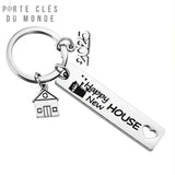 Porte clé nouvelle maison en acier inoxydable sur fond blanc avec inscription Happy New House, une petite maison et le symbole 2025
