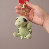 Porte clé tortue peluche verte tenu en main avec anneau et mousqueton dorés