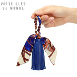 Porte clé pompon cuir bleu tenu en main, détail des franges en cuir et du ruban bohème avec anneau doré