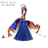 Porte clé pompon cuir bleu sur fond blanc avec franges et ruban style foulard, accessoire élégant pour sac et trousseau