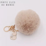 porte-clé pompon fourrure beige avec breloque chat sur fond blanc
