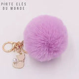Porte clé pompon en fourrure violet très douce avec anneau, mousqueton et petit chat blanc crème sur un fond blanc