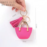 Porte clé sac femme rose tenu en main, accessoire féminin élégant en forme de mini sac avec pompon rose et anneau doré