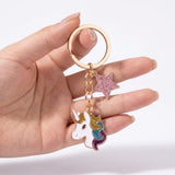 Porte-clé tête de licorne étoilé présenté dans une main, avec crinière multicolore pailletée et étoile rose