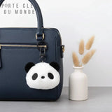 porte clé tête de panda blanc avec yeux noir accrocher sur un sac a main pour le mettre en situation 