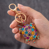 Porte clé tortue à motif doré et coloré tenu en main