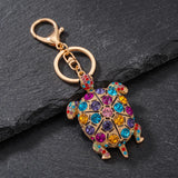 Porte clé tortue à motif doré avec strass multicolores sur fond ardoise
