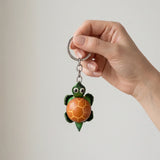 Porte clé tortue cuir coloris orange tenu en main