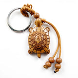 Porte clé tortue en bois sculpté avec anneau métallique et cordon décoratif sur fond blanc
