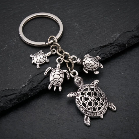 Porte clé tortue et son bébé avec plusieurs pendentifs tortue argentés sur fond sombre