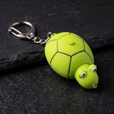 Porte clé tortue lampe LED verte posé sur fond noir