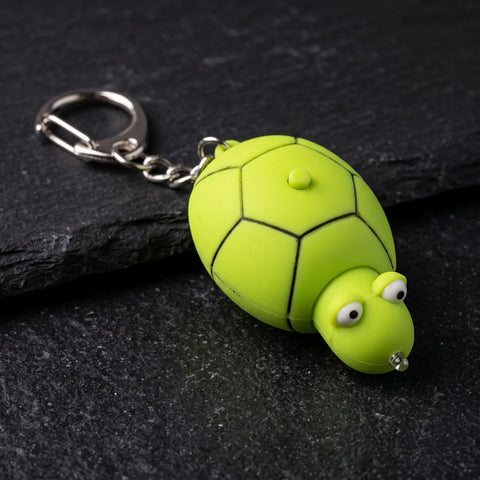 Porte clé tortue lampe LED verte posé sur fond noir