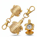 Porte clé tortue montre doré présenté sous plusieurs angles avec cadran analogique ouvert