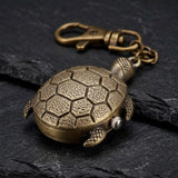 Porte clé tortue montre finition bronze avec carapace texturée sur fond sombre