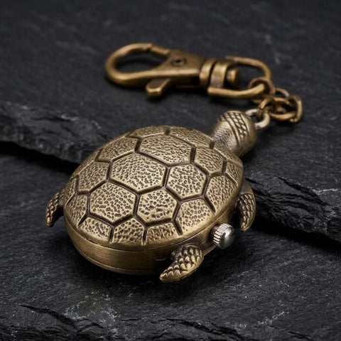 Porte clé tortue montre finition bronze avec carapace texturée sur fond sombre