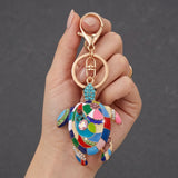 Porte clé tortue motif mosaïque multicolore tenu en main avec anneau et mousqueton dorés
