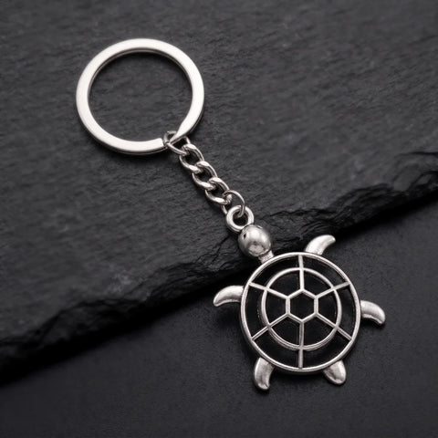 Porte clé tortue ajourée argentée avec carapace géométrique sur fond ardoise