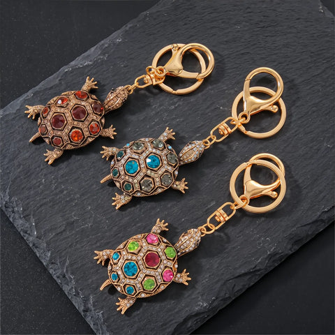 Trois porte clés tortue strass multicolore dorés sur fond ardoise