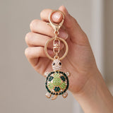 Porte clé tortue zircon vert et doré à strass tenu en main