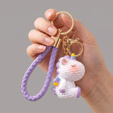 Porte-clef licorne Crochet, licorne blanche et violette avec lanière tressée, présentée dans une main