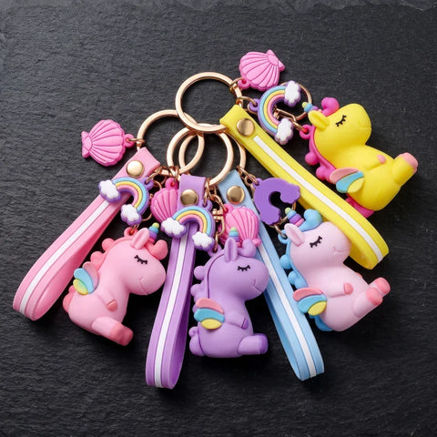 Porte-clés licorne emoji présentés en quatre coloris rose, violet, bleu et jaune avec dragonnes assorties