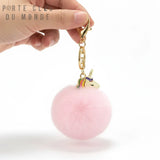 Porte clés licorne pompon rose pastel tenu en main, détail du pompon doux et du design licorne