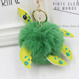 Porte-clé tortue pompon vu de haut sur fond blanc, carapace en pompon doux et design ludique